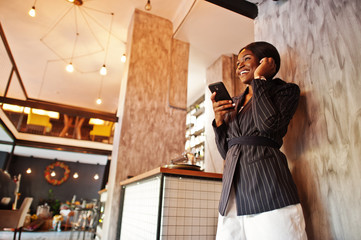 African american businesswoman in cafe with mobile phone. Black girl having rest.