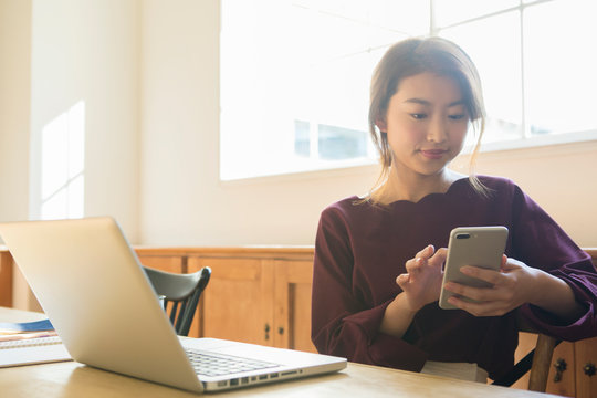 部屋でパソコンを操作する20代女性