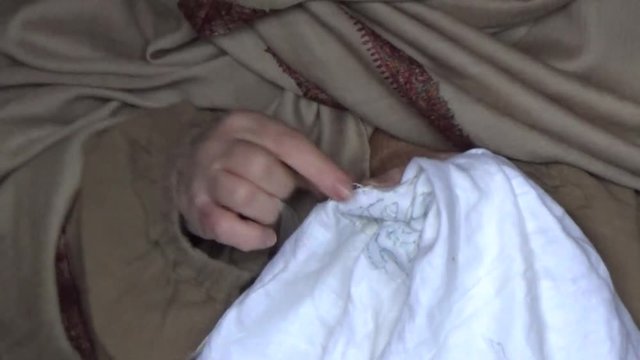 Женщина вышивает на белой ткани