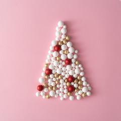 Christmas tree made of gold, red and white glitter ball decoration on pink. New Year greeting card party minimal style. Flat lay. Holiday concept.