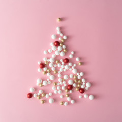 Christmas tree made of gold, red and white glitter ball decoration on pink. New Year greeting card party minimal style. Flat lay. Holiday concept.