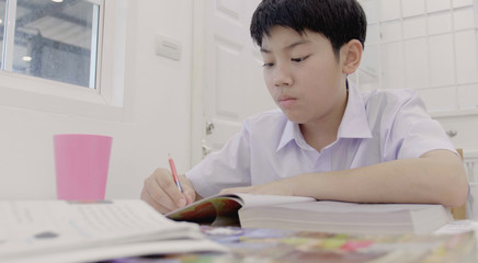 Asian child in student uniform to do homework at home.