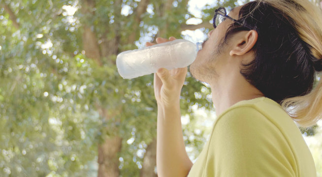 Asian sportsman drinks water from bottle .