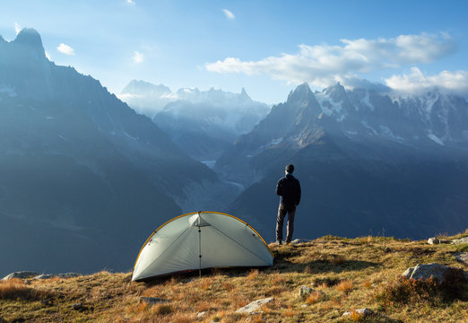 A hiker enjoying the awesome view and a cup of coffee at his campsite in the mountains.