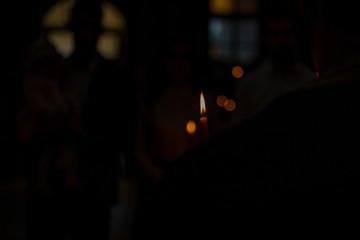 burning candle in a Christian church. a blurred background of a church and a candle during a Christian ritual, such as a wedding or a baptism. natural light and noisy effect.looking for a dark effect.