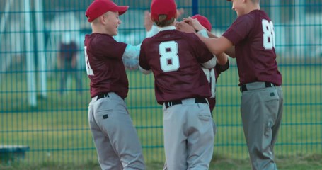 Kid boys baseball players cheering up their teammate after scoring. 4K UHD 60 FPS SLO MO - Powered by Adobe