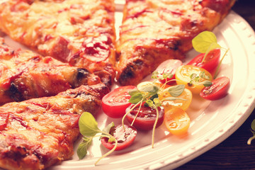 Homemade fresh pizza with tomatoes, cheese and mushrooms on wooden table closeup vintage view