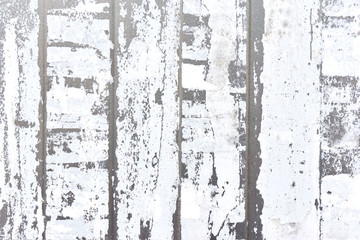 Close-up of vertical strips of white torn paper on a light gray metal background