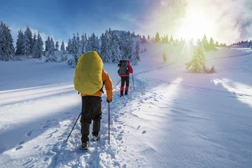 Afwasbaar Fotobehang Wintersport Winterwandelen. Toeristen wandelen in de besneeuwde bergen.