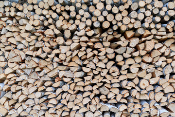 Large pile or stock of firewood for heating furnace. Logs and logs of birch. The log is split in half. Slice as a circle or semicircle. Background, backdrop or texture.