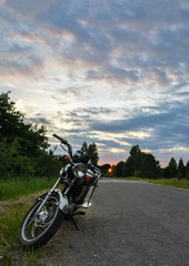 The moped on the road at sunset