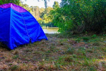 Blue camping tent in forest near a river