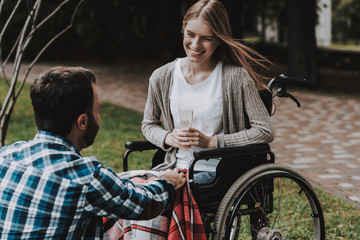 Girl on Wheelchairs with Man on Picnic in Park.