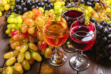 wine with branches of white grapes. On a wooden table.