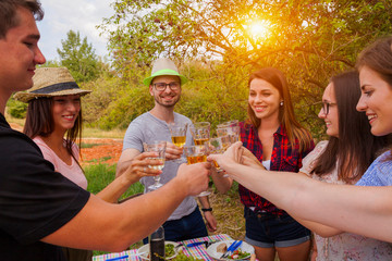 friends have a bbq party in the garden toasting with white wine. they enjoy a good meal with fresh ingredients.
