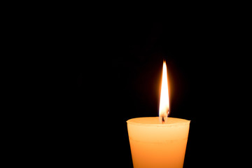 Portrait of one light candle burning brightly on black background. Close-up flame.