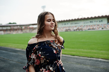 Portrait of a fabulous girl in dress and high heels on the track at the stadium.