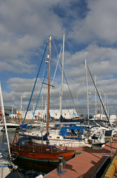 The different yachts near the quay on the sunny day.