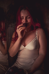 Girl with red hair enjoys the smell of plum
