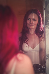 the girl with red hair looks in the mirror