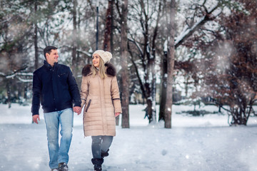 Fototapeta na wymiar Lovers walking in winter snow- Smiling Couple in Winter Park having fun..