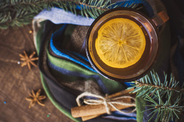 Cup of lemon tea covered with scarf. Christmas tree in background. Winter concept.