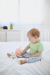 Fototapeta premium Baby girl sitting on bed and laughing
