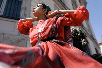 Portrait of a young woman in red clothes posing on the background  of old building in Warsaw, Poland. Fashion concept