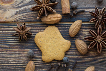 Gingerbread cookies with spices and almonds on brown wooden background. Bell shape, top view.