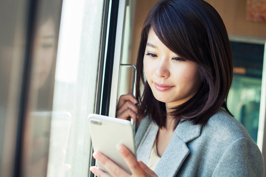 Young woman using smartphone while travelling by train