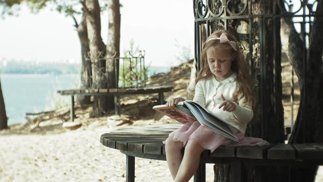 A sweet girl sits in the woods and reads a book