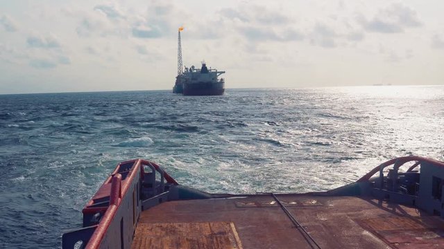 Anchor-handling Tug Supply AHTS vessel during dynamic positioning DP operations near FPSO tanker. Vessel is doing static tow tanker lifting. Ocean tug job.