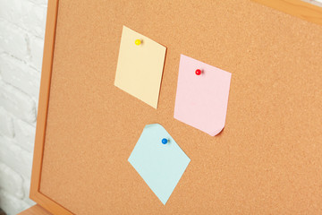 Sticky notes with pushpins and blank space on cork background. School or business concept