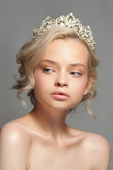Beautiful blond girl in the image of a bride with a tiara in her hair. Picture taken in the studio on a gray background. Beauty baby face. Wedding image. © hamara