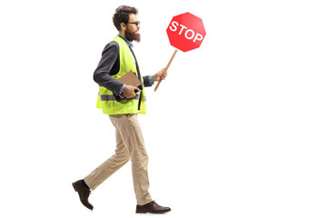 Man in a safety vest holding a stop traffic sign walking