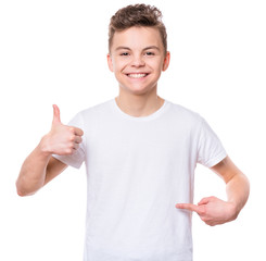 White t-shirt on teen boy. Handsome smiling child making thumbs up gesture, isolated on white background. Concept of childhood and fashion or advertisement design. Mock up template for design print. - 228513528