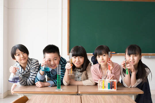 実験器具を持ち微笑む小学生