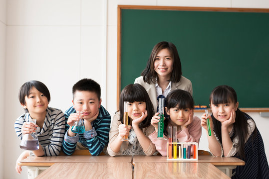 実験器具を持ち微笑む小学生と先生