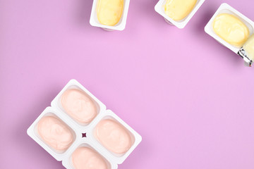 Plastic cup with tasty yogurt on lilac background. Top view. Space for text or design.