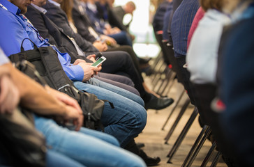 People sitting rear at the business conference. Sitting in their phone
