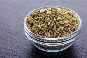Essential oil of fennel seeds on a dark stone background