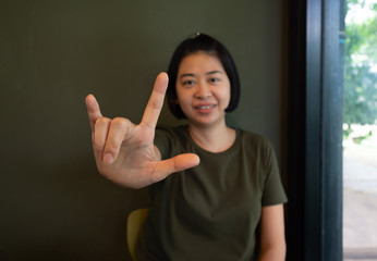 Asian woman using hand sign language I love you.