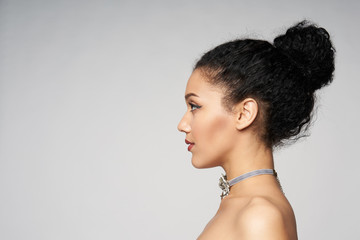 Beauty closeup profile portrait of beautiful mixed race caucasian - african american woman wearing chocker looking forward, isolated on gray background