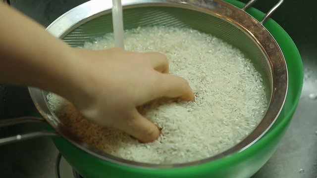 housewife washes rice in the kitchen for cooking pilaf at home