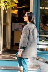 beautiful stylish woman in jacket near restaurant entrance