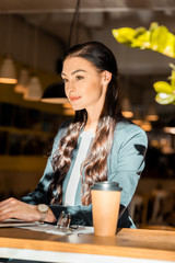 brunette freelancer working with laptop at cafe with coffee to go