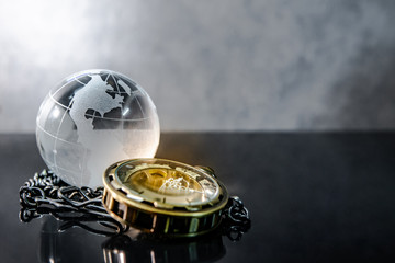 Global business concept. World globe crystal glass and silver pocket watch on glossy table. Time management and investment. 