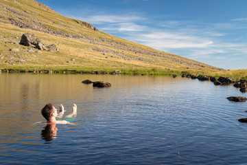 Man relaxing and enjoying refreshing bath in cold tarn water Lake District National Park, UK