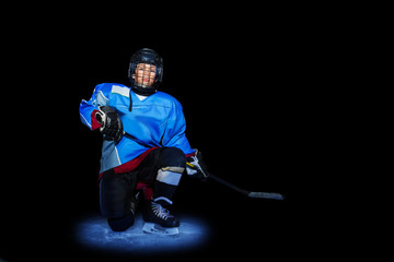 Young hockey player spotlighted on dark background