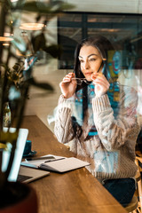 beautiful female freelancer in eyeglasses working in cafe